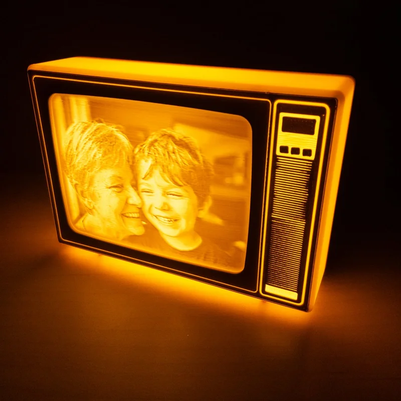 TV retro de Brilla encendida en la oscuridad, con la foto de una abuela y su nieto abrazados iluminada en luz cálida