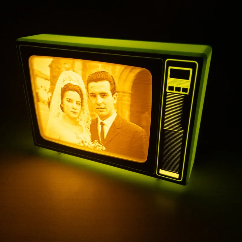 TV retro verde de Brilla encendida en la oscuridad; la luz cálida dibuja en la pantalla abombada una foto de boda antigua, la novia con velo de encaje y el novio de traje y corbata