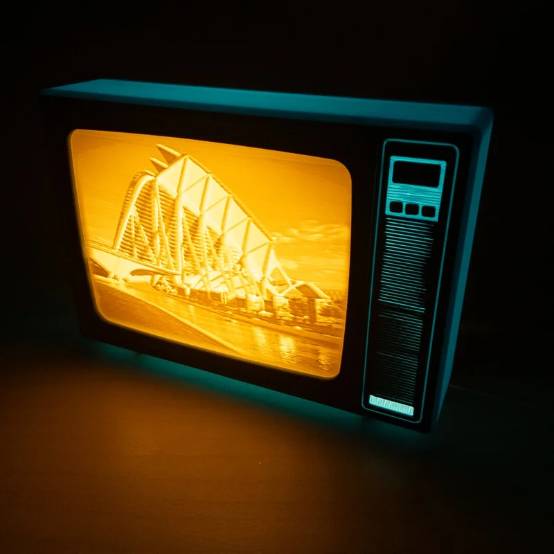 TV retro azul encendida en la oscuridad con la litofanía del Museo de las Ciencias de Valencia, con sus arcos blancos junto al agua, en tonos ámbar